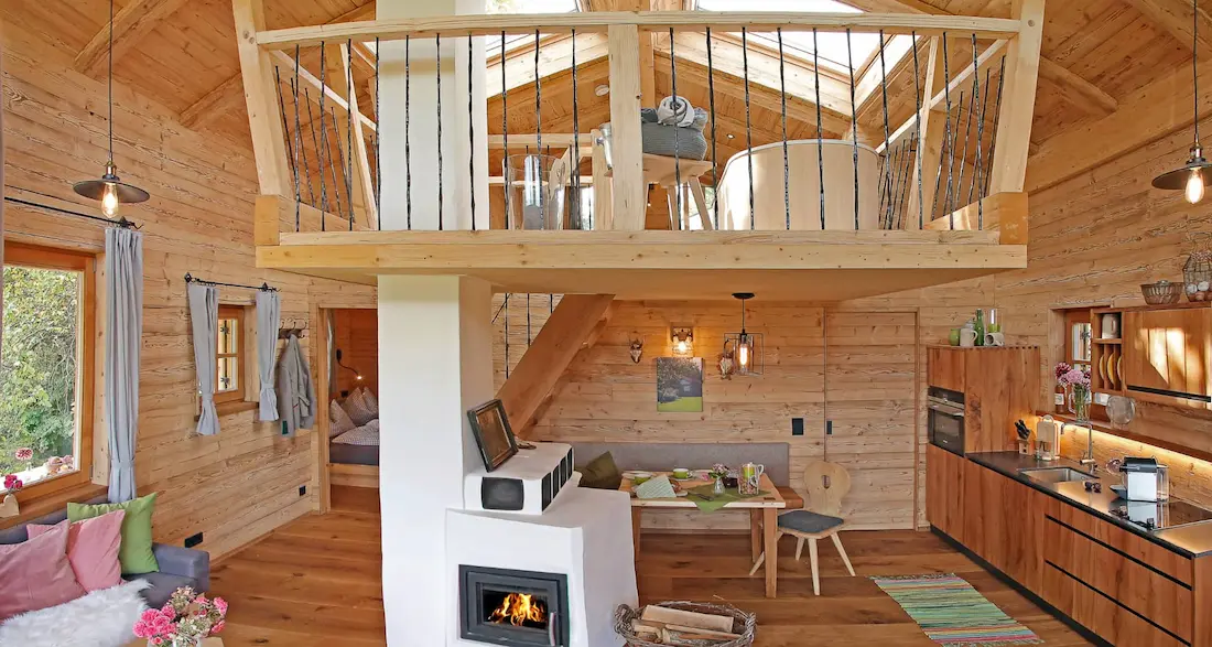 Das Alm-Chalet Chiemsee Wohnraum mit Kachelofen und Empore